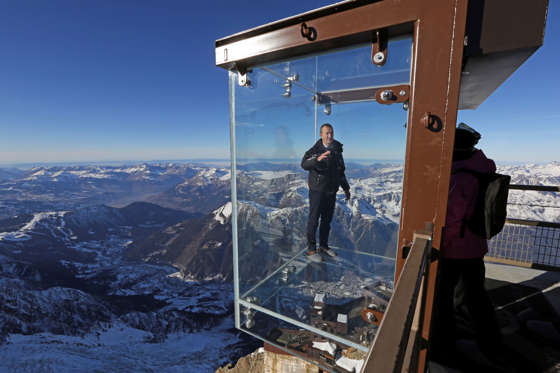 Mathieu Dechavanne, head of the Compagnie du Mont Blanc which runs the new attraction, stands in a glass cage named 'Pas dans le Vide' (Step into the Void) at the top of the Aiguille du Midi peak (3842-meters high or 12,604 feet), in the French Alps, during a press visit. Visitors can enjoy the view of Mont Blanc, Europe's highest mountain, from the platform. The attraction opens Saturday.