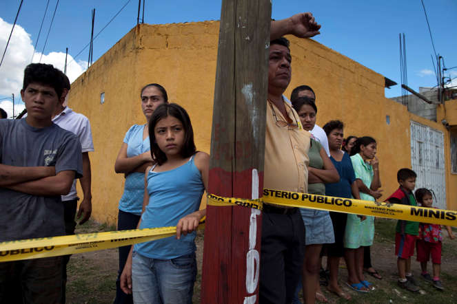 People stand behind police tape at a crime scene in Guatemala City.