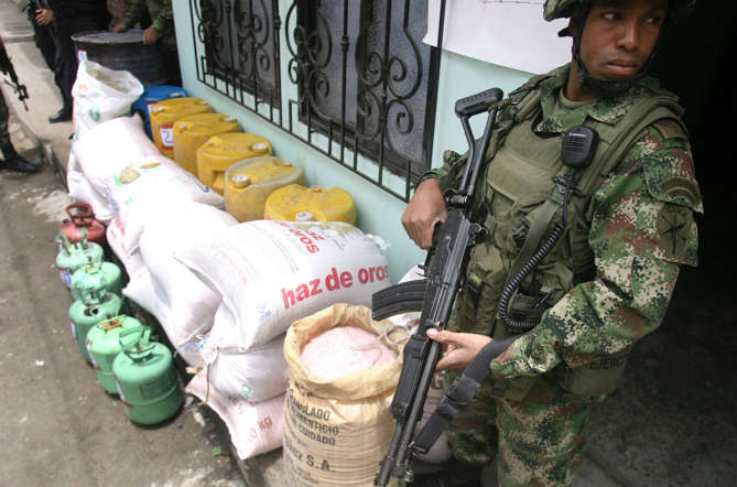A soldier stands guard alongside at least 700 kg of explosives seized by army troops during a raid close to Palmira city.