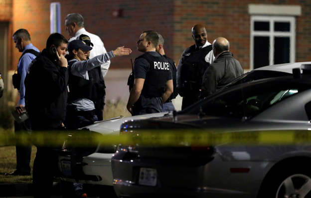 Police investigate the scene where two police officers were shot outside the Ferguson Police Department, March 12, 2015, in Ferguson, Mo.