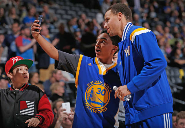 A fan takes a selfie with Stephen Curry of the Golden State Warriors as the Warriors face the Denver Nuggets on March 13, 2015, at the Pepsi Center in Denver.
