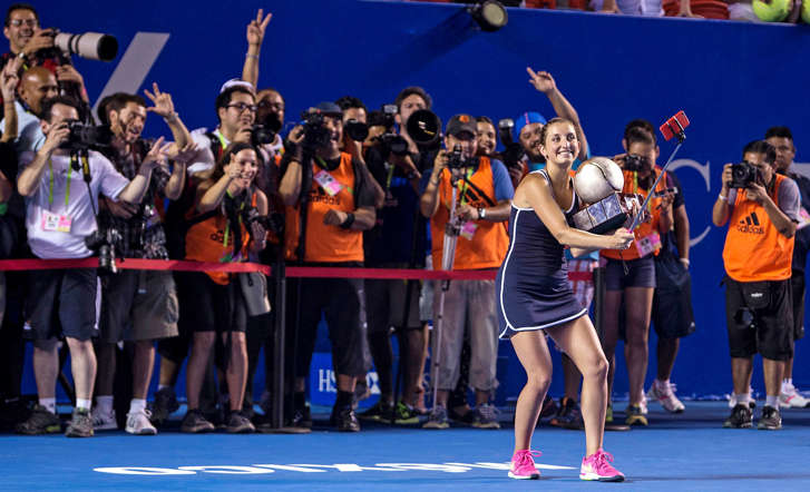 Timea Bacsinszky of Switzerland uses a selfie stick to take a photo of herself holding the trophy after she defeated Caroline Garcia of France to win the Mexico Open tennis tournament on Feb. 28, 2015, in Acapulco, Mexico.
