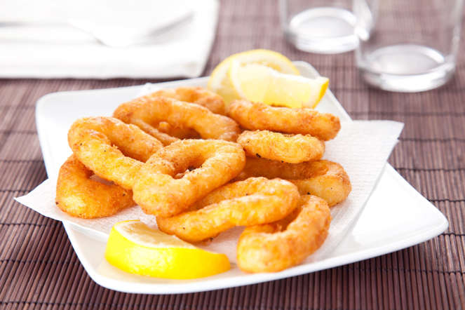 Calamari rings covered in a thick batter and deep fried are served with a sprinkle of lemon juice and dollops of mayonnaise.