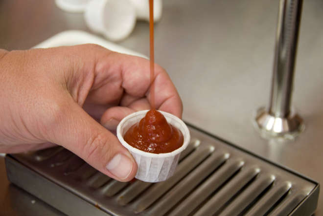 Man pouring ketchup into paper cup