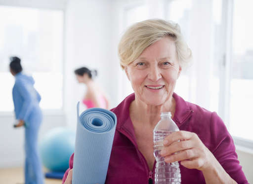 Caucasian woman with yoga mat drinking water
