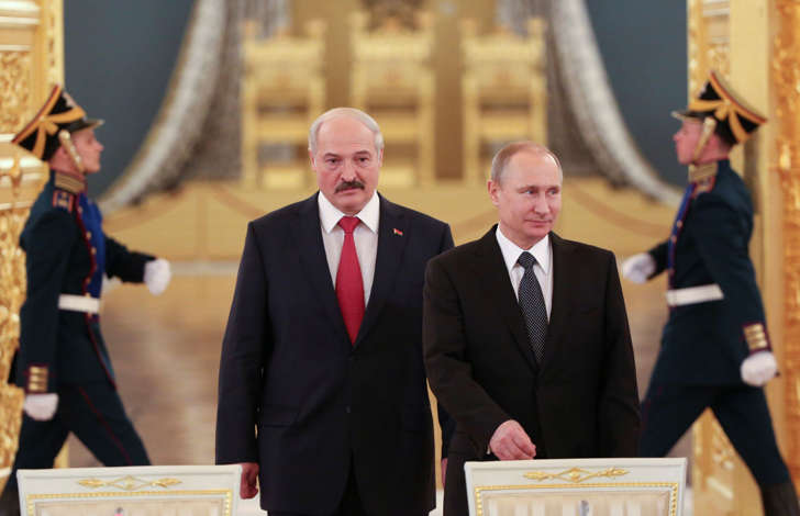 Belarussian President Lukashenko walks with Russian President Putin  past honor guards as they attend a session of the Supreme State Council.