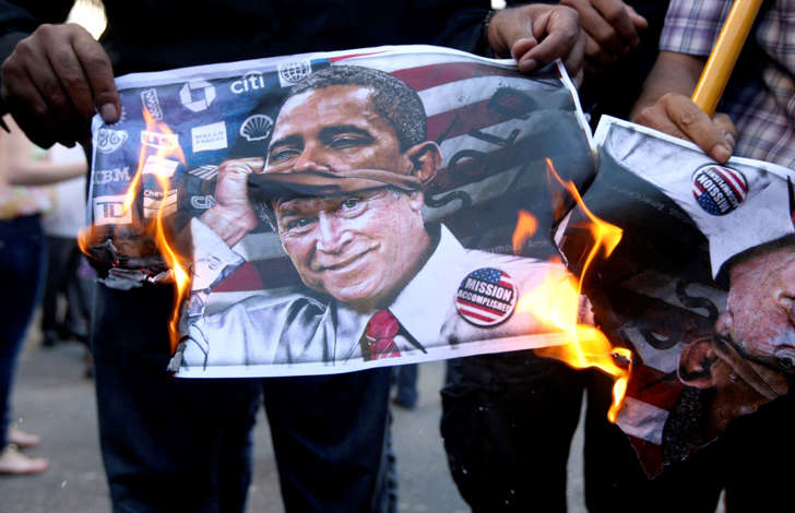 Activists burn a poster of Bush disguised as Obama during a protest in Awkar, Lebanon.
