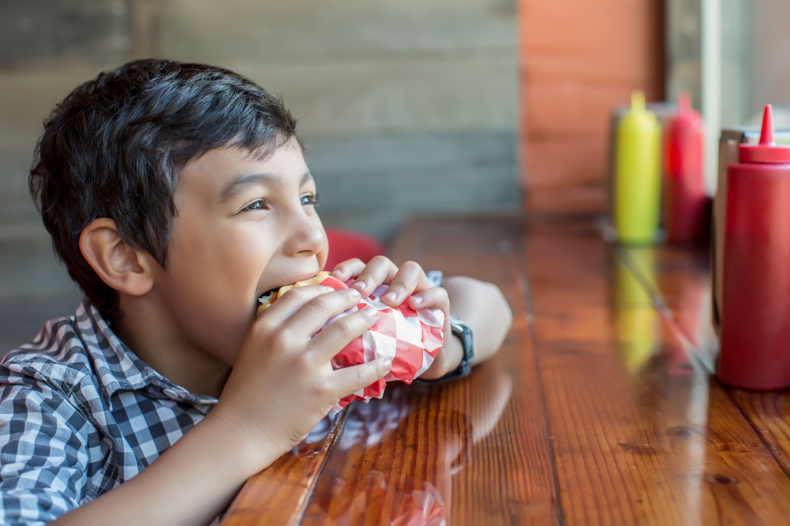 Mixed race boy eating burger in restaurant