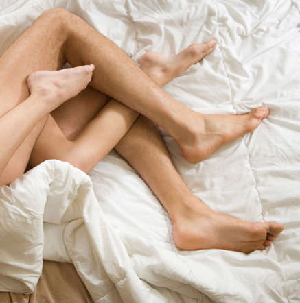 A man & a woman with their legs entwined - Neil Beckerman/Getty Images