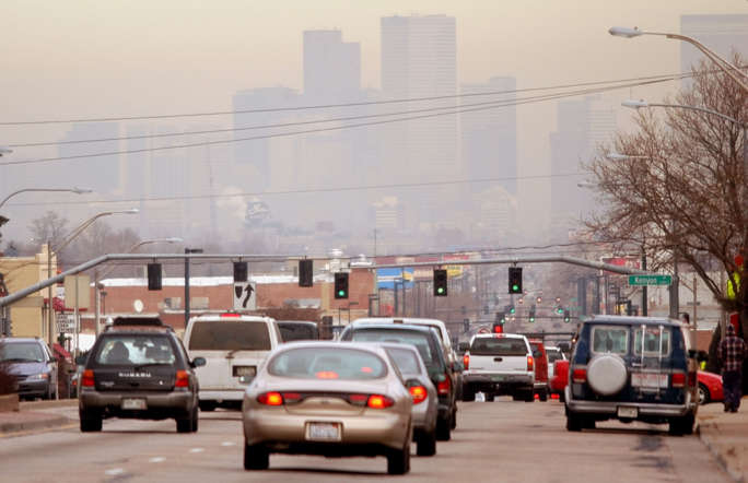Vehicles head inbound on South Broadway, polluted air obscures the view of the skyline of Denver