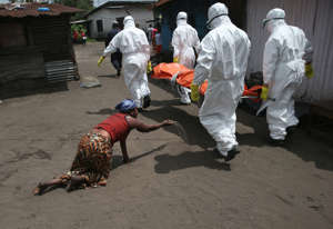 Uma mulher joga um punhado de terra em direção ao corpo de sua irmã como Ebola membros da equipe enterro levá-la para a cremação em 10 de outubro de 2014, em Monróvia, Libéria.