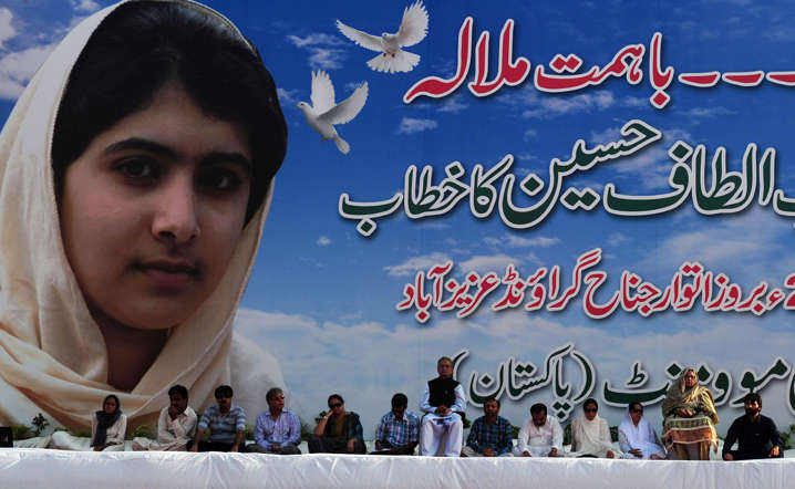 Pakistani leaders of the Muttahida Quami Movement (MQM) sit beside a photograph of child activist Malala Yousafzai during a protest procession against the assassination attempt by Taliban, in Karachi on October 14, 2012.  A Pakistani schoolgirl Malala Yousafzai shot in the head by the Taliban because she campaigned for the right to education is making 'slow and steady progress' in her recovery, the military said.