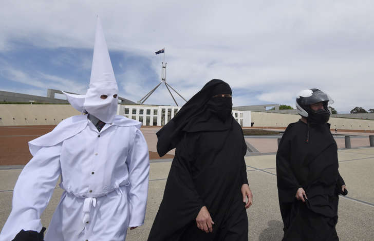 Protesters wearing face coverings are seen outside Parliament House in Canberra
