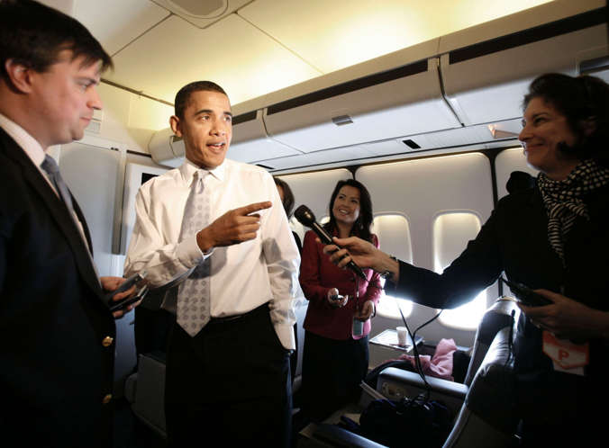 U.S. President Barack Obama speaks to the press as he walks through the press cabin aboard Air Force One.