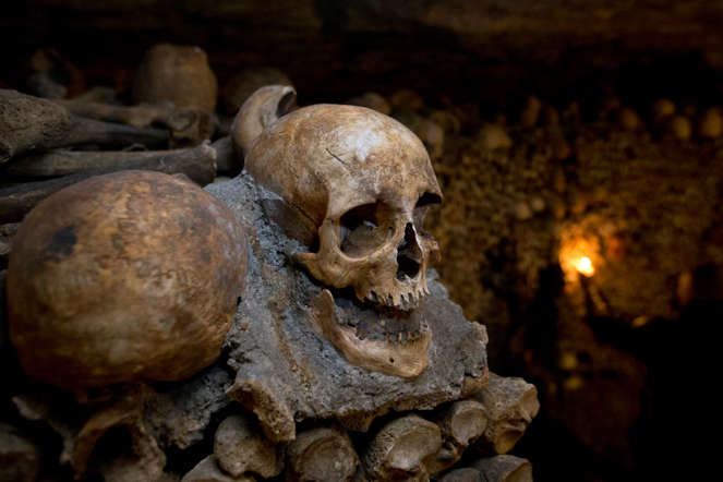In this photo taken Tuesday, Oct. 14, 2014, skulls and bones are stacked in the Catacombs of Paris, France. As if visiting the Paris Catacombs in the daytime weren't creepy enough,  you can now visit the underground maze of skeletons at night, too. The subterranean tunnels, stretching 2 kilometers (1.2 miles), cradle the bones of some 6 million Parisians from centuries past and once gave refuge to smugglers. (AP Photo/)