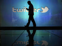 Man checking phone in front of Twitter logo.