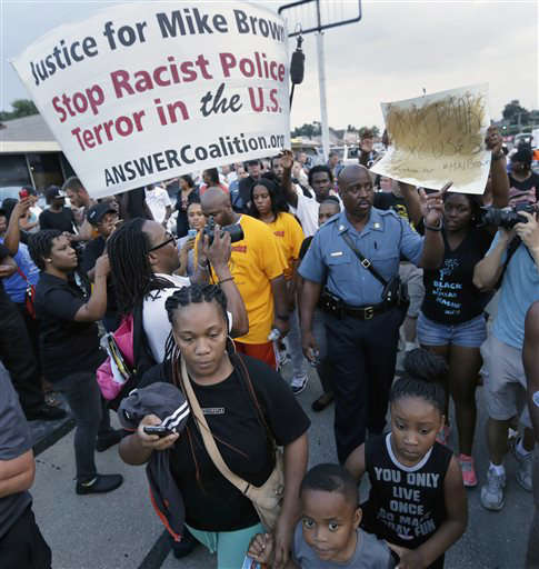 In this Aug, 16, 2014 file photo, Missouri Highway Patrol Capt. Ron Johnson walks among people protesting the police shooting death of Michael Brown in Ferguson, Mo.
