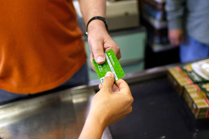 A cashier receives a credit card from a customer for payment at a market in Florida.