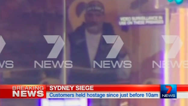 A man is seen standing behind the window of the Lindt cafe, where hostages are being held.