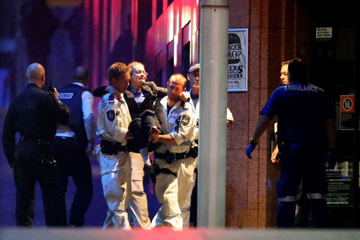 Police carry a woman from a cafe in Sydney Australia after the conclusion of a hostage standoff on December 15, 2014.