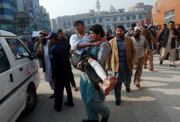 A man carries an injured student after he received treatment at a hospital in Peshawar, Pakistan, December 16, 2014.