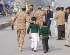 A soldier escorts schoolchildren after they were rescued from the Army Public School that is under attack by Taliban gunmen in Peshawar, December 16, 2014.
