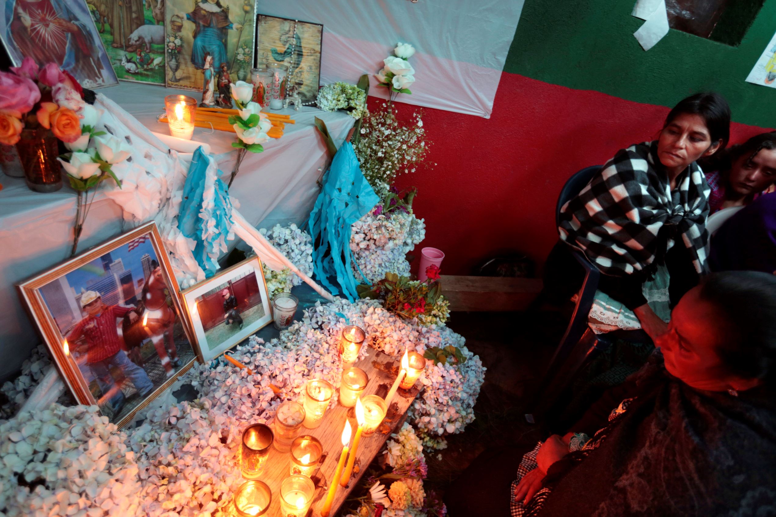 Cipriana Juarez (top), mother of teenage migrant Gilberto Francisco Ramos Juarez, and an unidentified woman stand in front of an altar, with a picture of Ramos Juarez, during his funeral in San Jose Las Flores, Chiantla, in the Huehuetenango region, north of Guatemala City, on July 12, 2014. Ramos Juarez's body was found in the Rio Grande Valley of southern Texas, less than a mile from the U.S.-Mexico border.