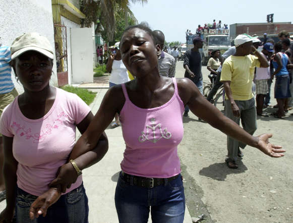 A woman mourns after victims of a boat accident were placed into a communal grave in Cap-Haitien, Haiti. A boat brought back Haitian immigrants who died when their sailboat capsized as they headed to the United States.