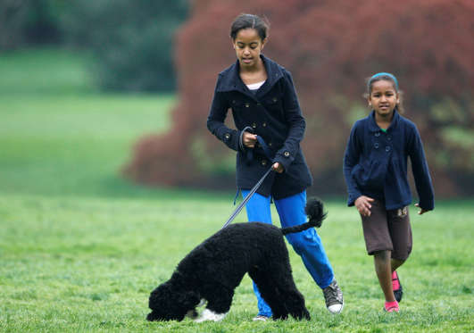 Malia Obama (L) and Sasha Obama walk their Portuguese water dog Bo in the White House.