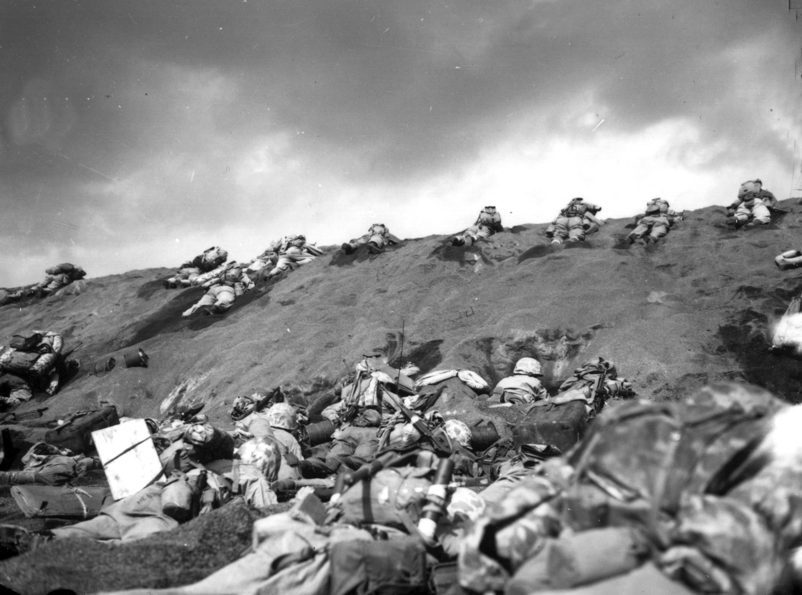 U.S. Marines of the 5th Division inch their way up a sand dune on Red Beach No. 1 toward Mount Suribachi, as the smoke of the battle drifts over them during the initial invasion on Iwo Jima, on February, 19, 1945. (AP Photo)