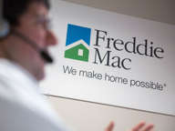 A Freddie Mac sign hangs behind employee John Estrada as he works in the borrower contact unit area at Freddie headquarters in McLean, Virginia, U.S., on Tuesday, April 8, 2014.