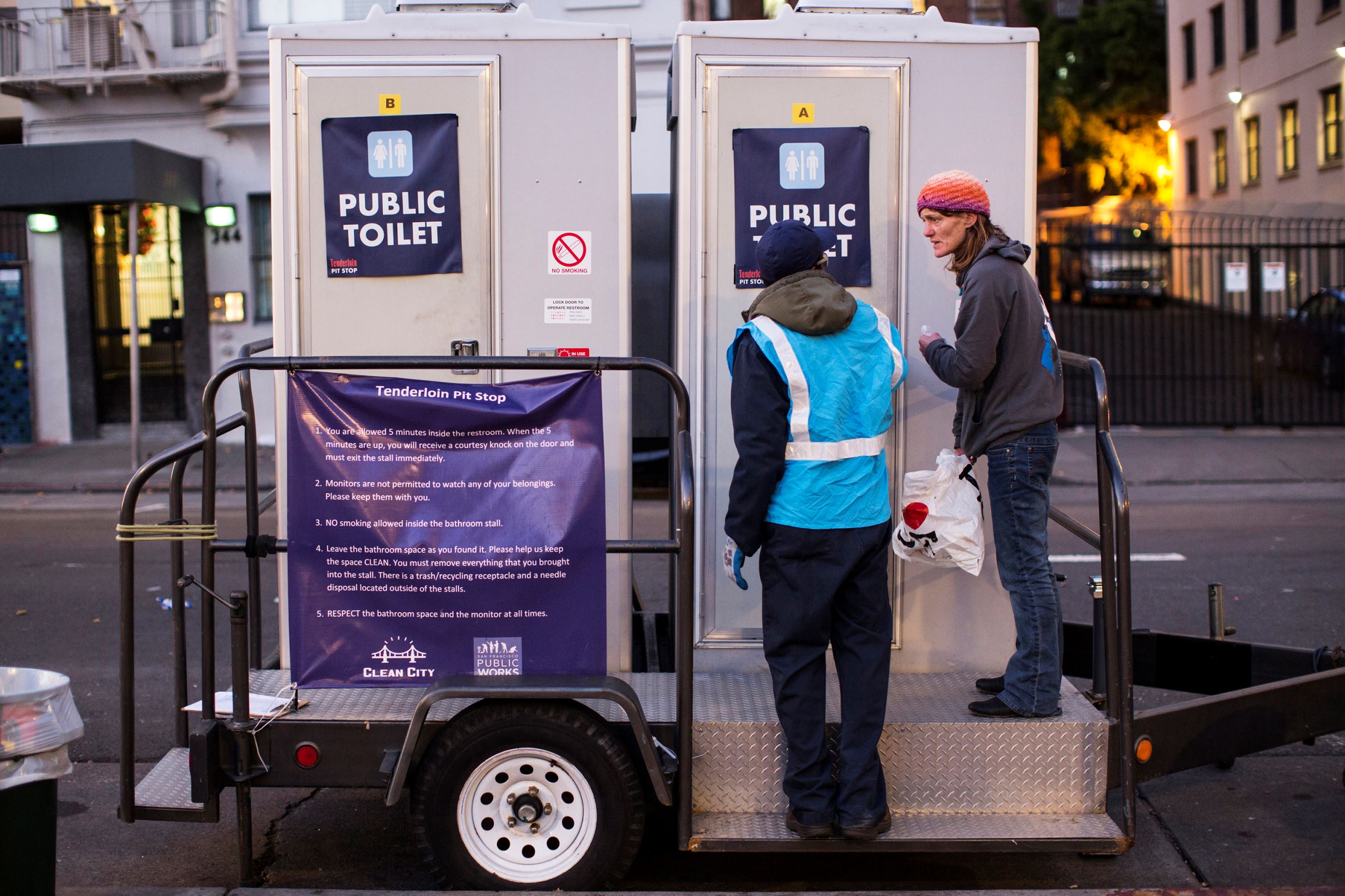 An attendant, left, speaks with a visitor as he unlocks the door to a toilet in the Tenderloin District in San Francisco, California December 30, 2014. Operated by the San Francisco Department of Public Works, the solar-powered toilets are part of a six-month pilot project aimed to provide clean and secure portable toilets, used needle disposal and dog waste stations throughout the Tenderloin District in an effort to alleviate the problem of human feces on the streets.