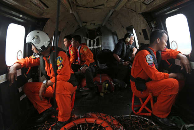 Crewmembers of an Indonesian Air Force NAS 332 Super Puma helicopter look out of the windows during a search operation for the victims and wreckage of AirAsia flight QZ 8501 over the Java Sea, Indonesia, January 5, 2015.