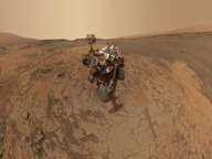 This self-portrait of NASA's Curiosity Mars rover shows the vehicle at the "Mojave" site, where its drill collected the mission's second taste of Mount Sharp. The scene combines dozens of images taken during January 2015 by the Mars Hand Lens Imager camera at the end of the rover's robotic arm.  The pale "Pahrump Hills" outcrop surrounds the rover, and the upper portion of Mount Sharp is visible on the horizon.  Darker ground at upper right and lower left holds ripples of wind-blown sand and dust.
