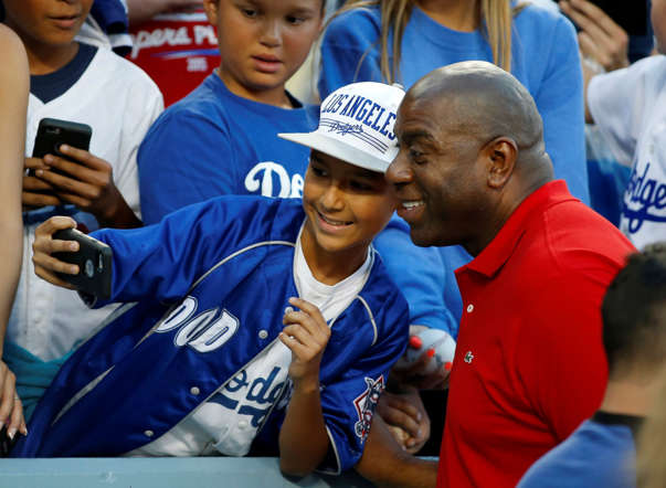 Los Angeles Dodgers owner Earvin "Magic" Johnson poses for a selfie cell phone photo with a young fan before the baseball game between the Los Angeles Dodgers and San Francisco Giants at Dodger Stadium on April 28 in Los Angeles.
