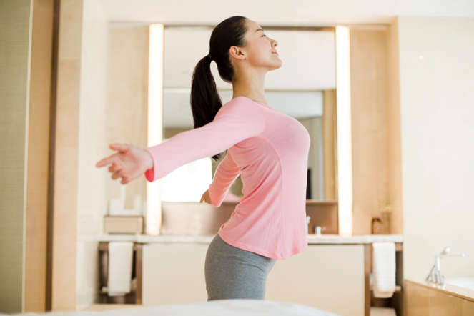Young woman stretching in bedroom