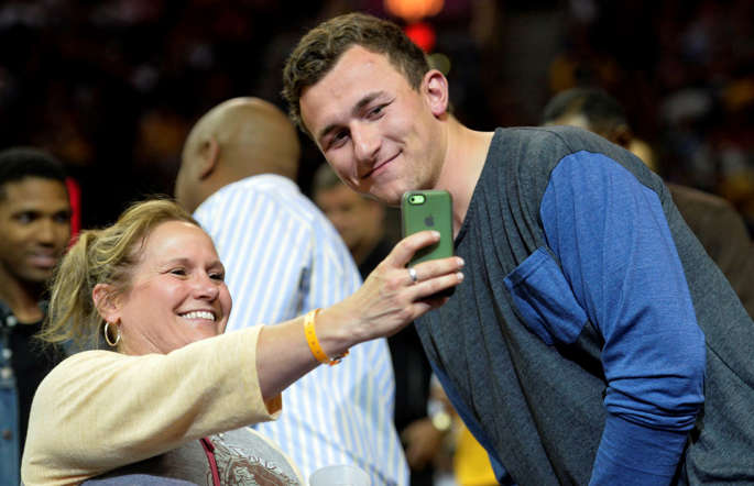 Cleveland Browns quarterback Johnny Manziel poses for a photograph with a fan during game five of the second round of the NBA Playoffs on May 12 in Cleveland.