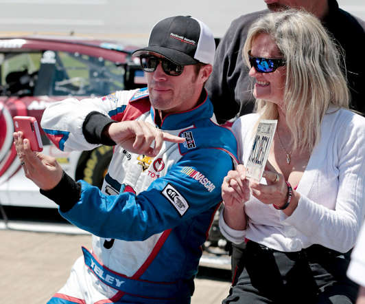 NASCAR driver J.J. Yeley takes a selfie with a race fan during qualifying for a Sprint Cup Series auto race at Talladega Superspeedway on May 2, 2015, in Talladega, Ala.