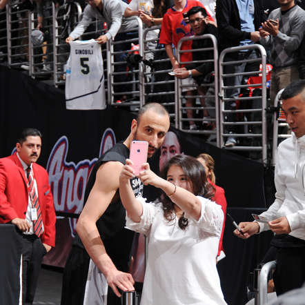Manu Ginobili of the San Antonio Spurs poses for a selfie with a fan before a playoff game against the Los Angeles Clippers on April 22, 2015, at the Staples Center in Los Angeles.