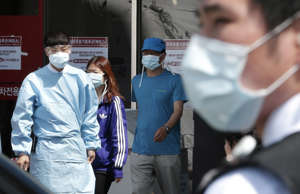 Hospital workers and visitors wearing masks pass by a precaution against the MERS, Middle East Respiratory Syndrome, virus at a quarantine tent for people who could be infected with the MERS virus at Seoul National University Hospital in Seoul, South Korea, Wednesday, June 3, 2015.