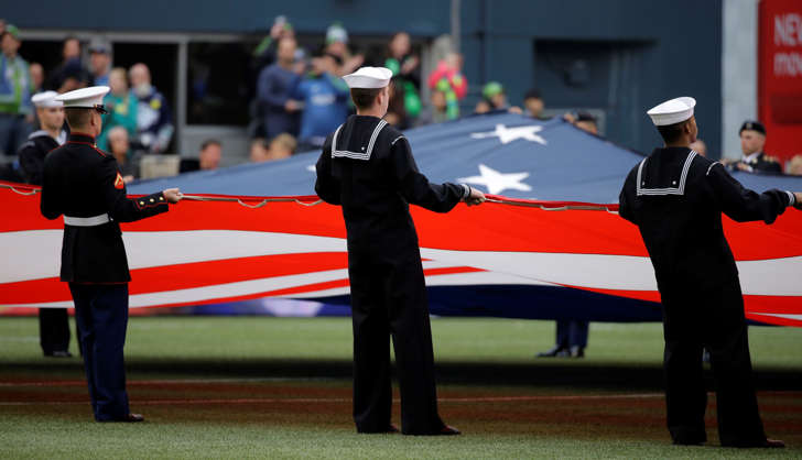 Members of the military hold a giant U.S. flag before an MLS soccer match between the Seattle Sounders and Sporting Kansas City, in Seattle, May 23, 2015.