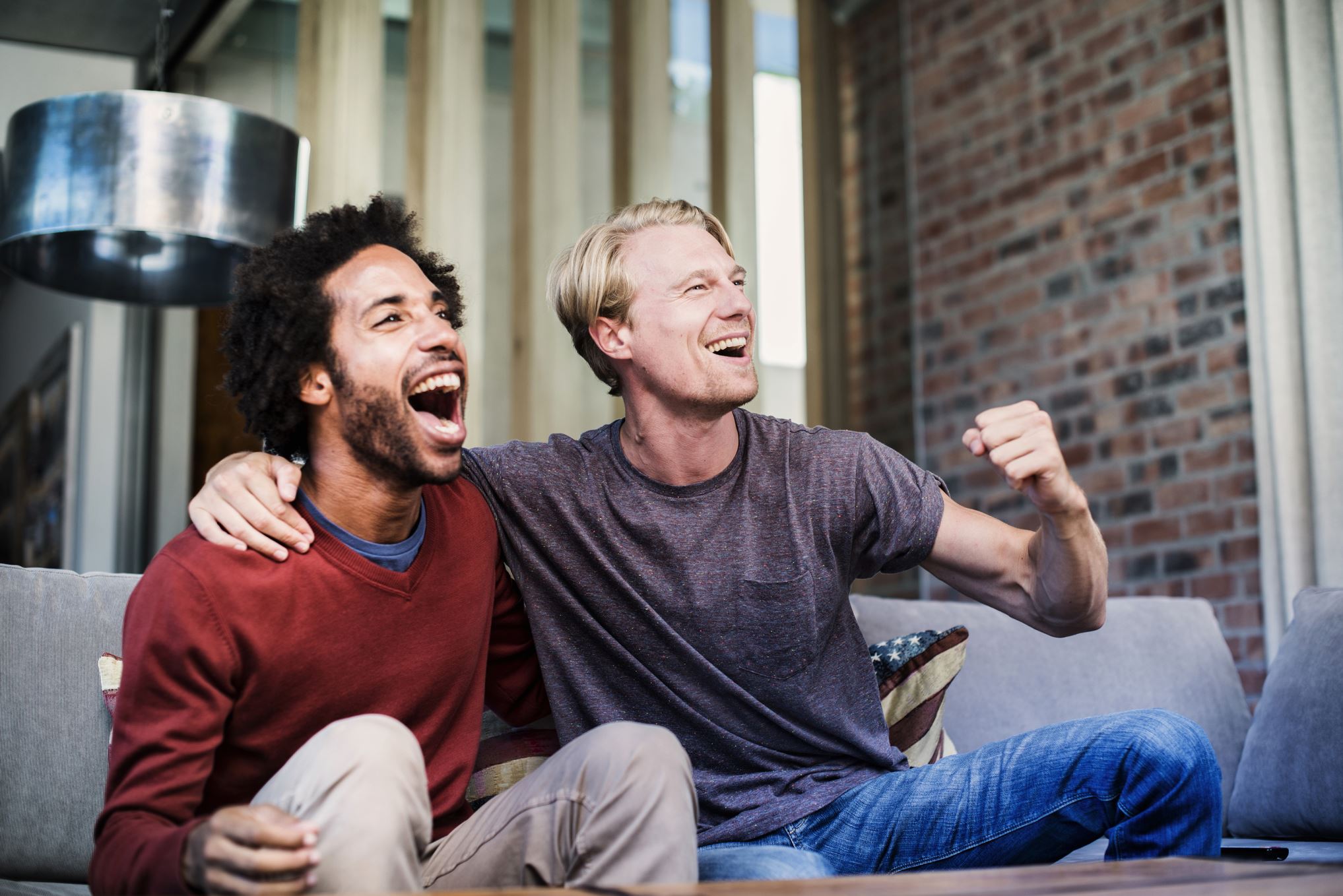 Men friends cheering sports team on tv