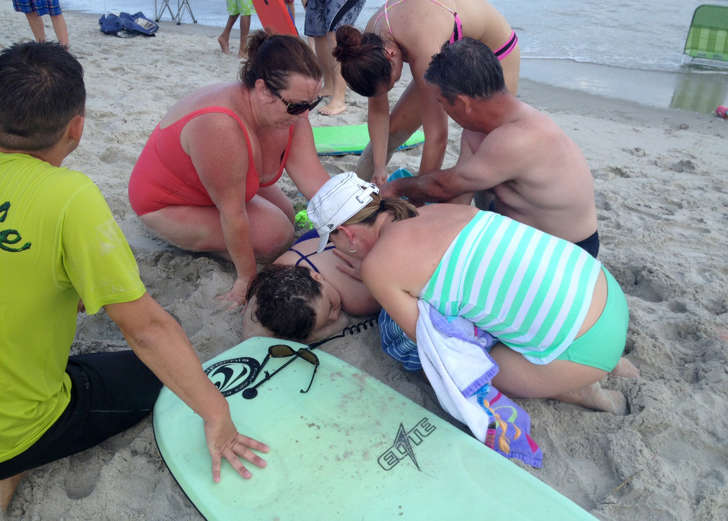 People assist a teenage girl at the scene of a shark attack in Oak Island, N.C., June 14, 2015.