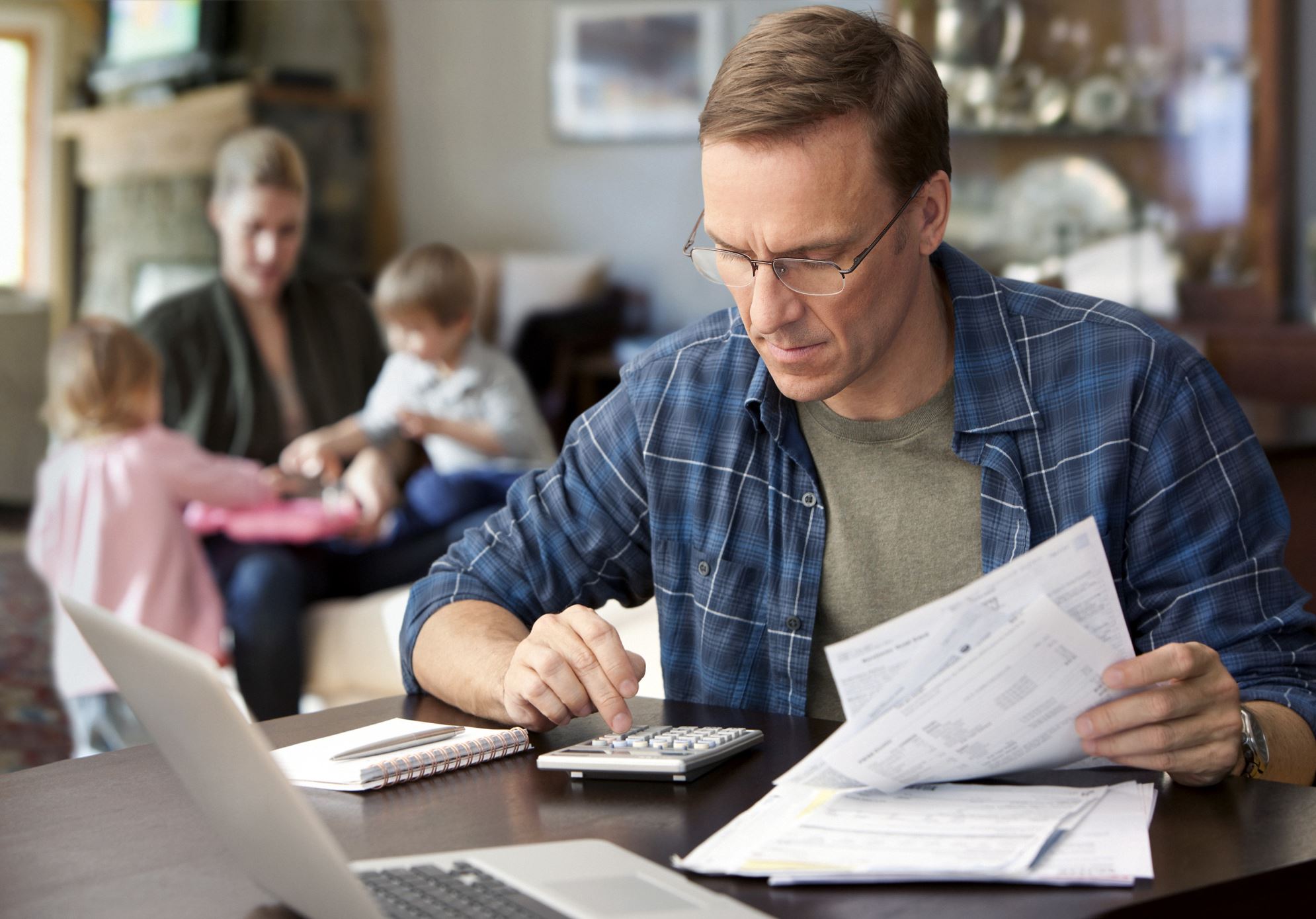 ​Father paying bills with family behind him.
