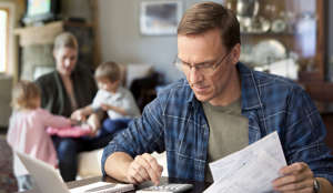 ​Father paying bills with family behind him.