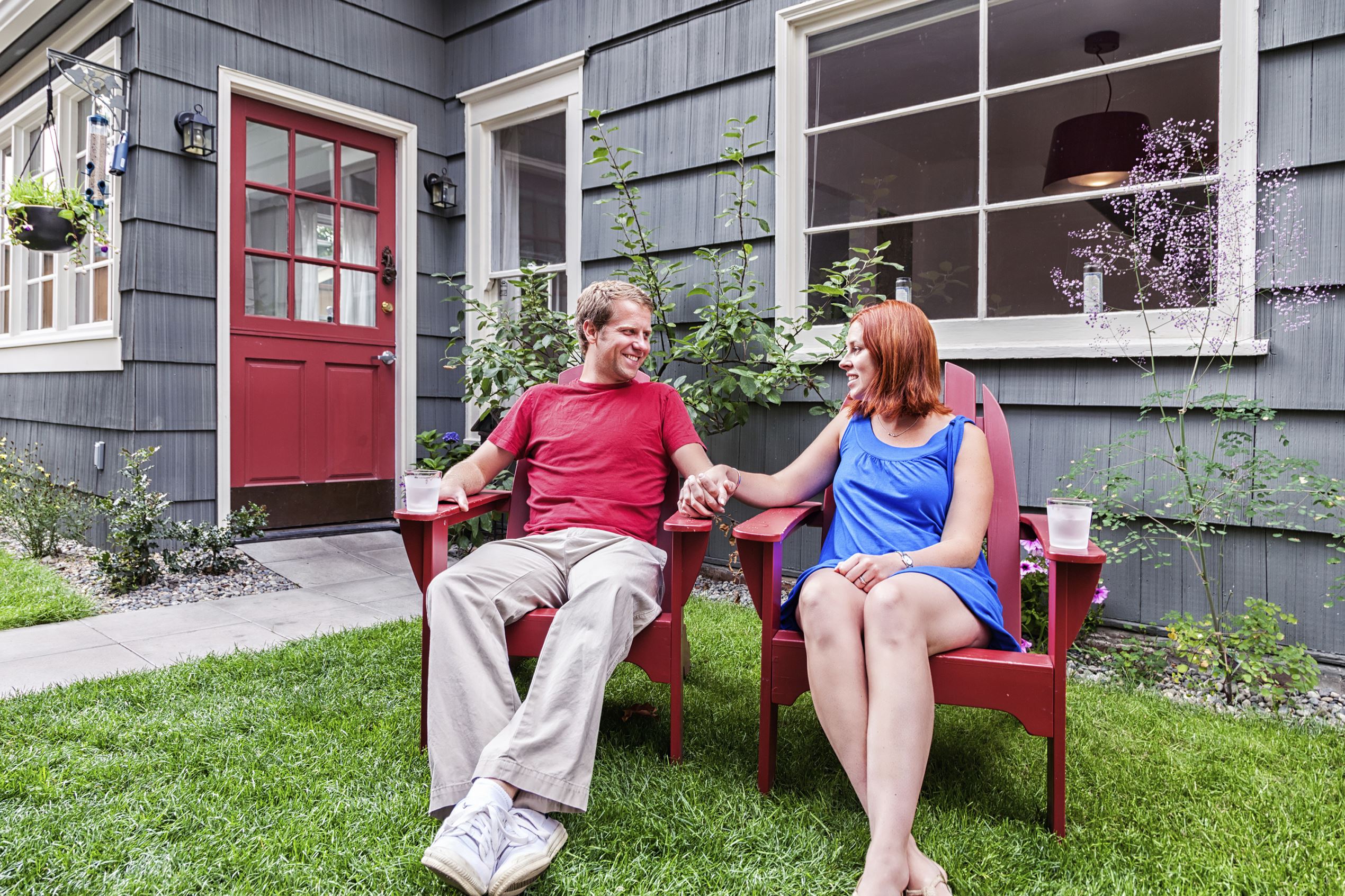 Photo of a happy young couple enjoying a summer day, sitting on lawn furniture in the back yard of their home.