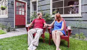 Photo of a happy young couple enjoying a summer day, sitting on lawn furniture in the back yard of their home.