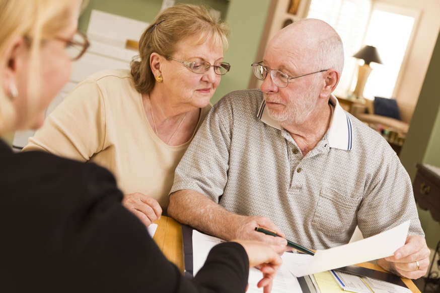 Senior Adult Couple Going Over Papers in Home with Agent.