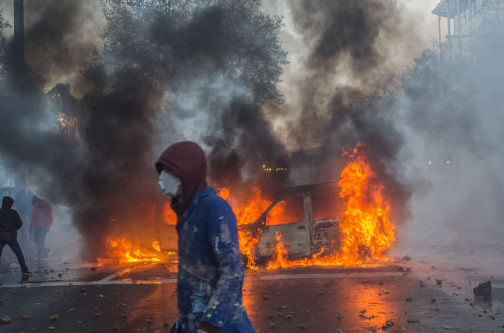Vehicles are set on fire in the street as protesters clash with riot police after a huge rally in Brussels against the new centre-right government's austerity policies.