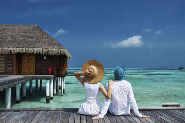 Couple on a tropical beach jetty. Haveseen/Getty Images